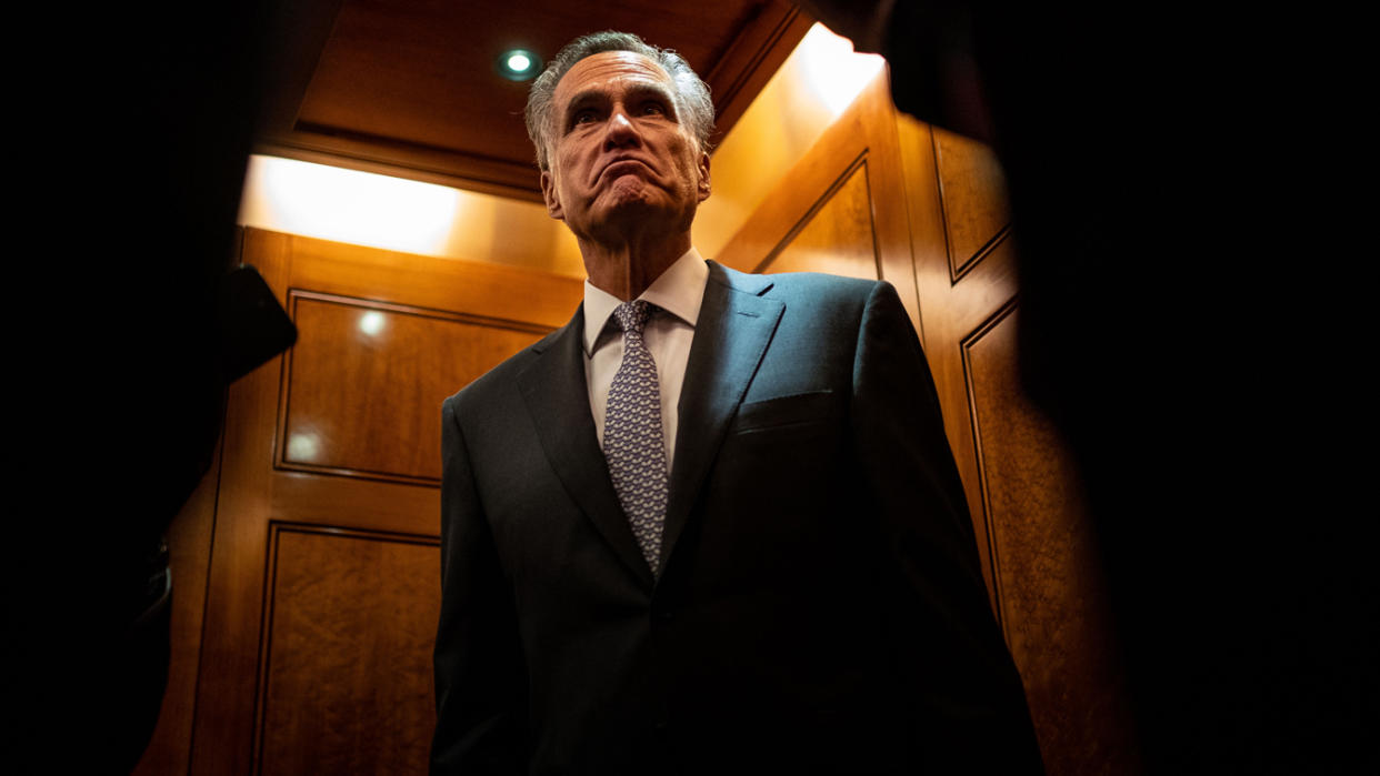 Sen. Mitt Romney, seen against a backdrop of wood paneling, looks skeptical. 