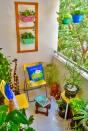 The cosy balcony garden accommodates a sit-out space. The tiered plant-holder in the far corner is a repurposed vegetable storage unit and the wooden wall frame has been upcycled from packing material.