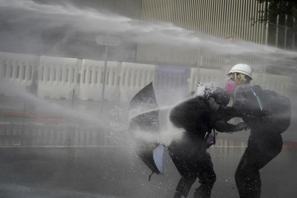 Anti-government protesters are sprayed with water cannon during a demonstration near Central Government Complex in Hong Kong, Sunday, Sept. 15, 2019. Police fired a water cannon and tear gas at protesters who lobbed Molotov cocktails outside the Hong Kong government office complex Sunday, as violence flared anew after thousands of pro-democracy supporters marched through downtown in defiance of a police ban. (AP Photo/Vincent Yu)