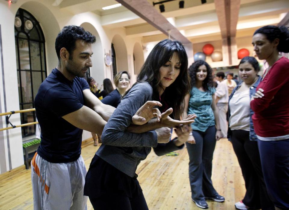 FILE - In this Thursday, Feb. 7, 2013 file photo, Soraya Bahgat, founder of the anti-harassment group Tahrir Bodyguard, tries a self-defense move on instructor Ramy Jerair Latchinian, left, at a workshop for women organized by the group in response to a recent spate in sexual violence against female protesters in Cairo, Egypt. Women activists say they won a major step forward with Egypt’s new constitution, which enshrined greater rights for women. But months after its passage, they’re worrying whether those rights will be implemented or will turn out to be merely ink on paper. Men hold an overwhelming lock on decision-making and are doing little to bring equality, activists say, and the increasingly repressive political climate is stifling chances for reforms. (AP Photo/Maya Alleruzzo)