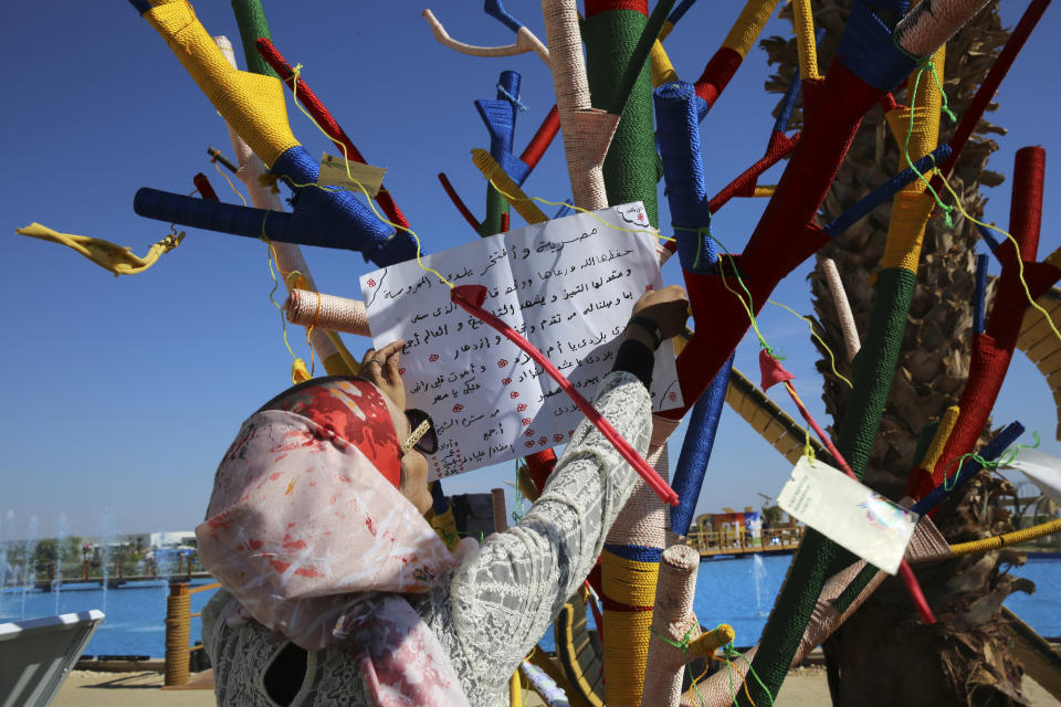 An Egyptian woman posts a patriotic message on an artificial tree set up for people to hang a note saying what promise they will make to help fight climate change, in the Green Zone of the COP27 U.N. Climate Summit, in Sharm el-Sheikh, Egypt, Friday, Nov. 18, 2022. (AP Photo/Thomas Hartwell)