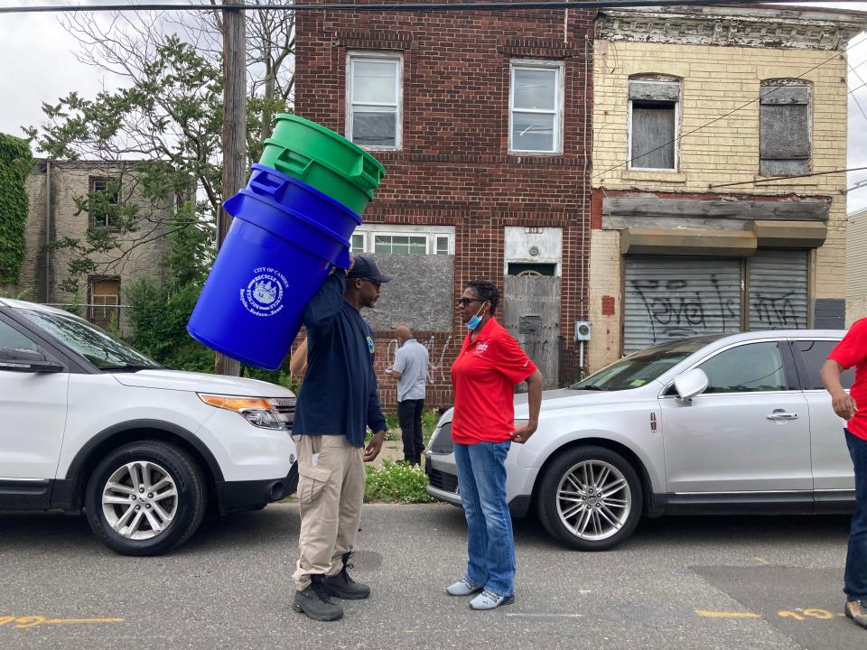 Camden's director of public works, Keith Walker, talks with Councilwoman Sheila Davis as workers hand out trash and recycling bins to residents in Lanning Square on Tuesday.