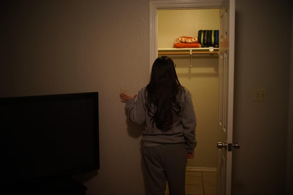 A woman is seen from behind inspecting a closet.