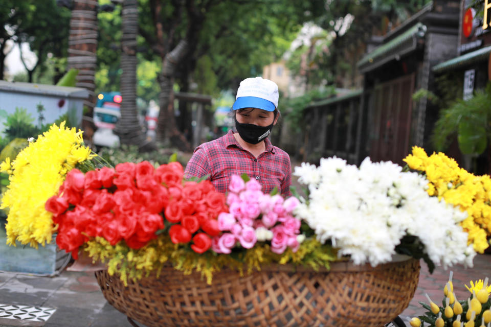 A flower vender wearing a face mask to protect against the coronavirus waits for customers in Hanoi, Vietnam, Monday, Aug. 3, 2020. Vietnam has tightened travel and social restrictions after the country's death toll of COVID-19 to six. (AP Photo/Hau Dinh)