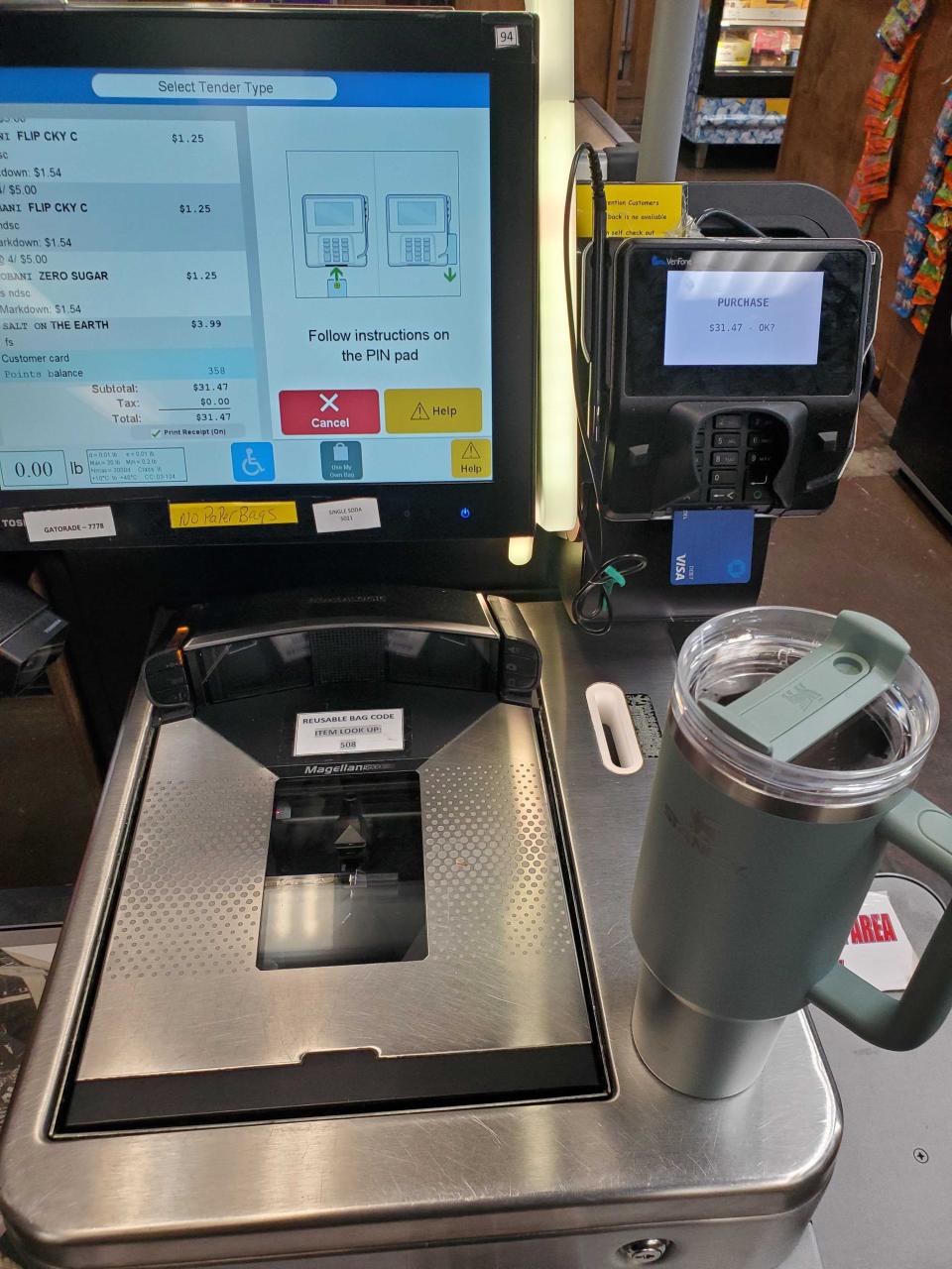 Teal Stanley cup sits next to a self-checkout station inside a convenience store.