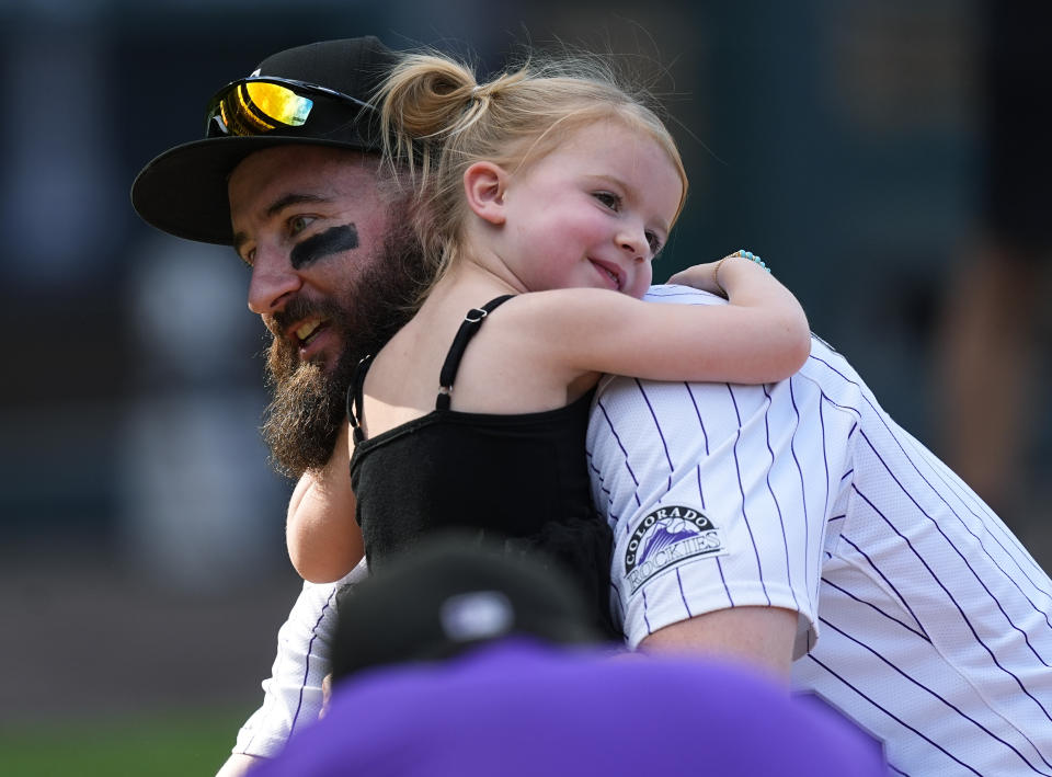 Retiring Colorado Rockies outfielder Charlie Blackmon, left, is hugged by his 3-year-old daughter Josie, right, during the team's ceremonial walk around the field to acknowledge fans following a baseball game loss to the Los Angeles Dodgers, Sunday, Sept. 29, 2024, in Denver. (AP Photo/David Zalubowski)