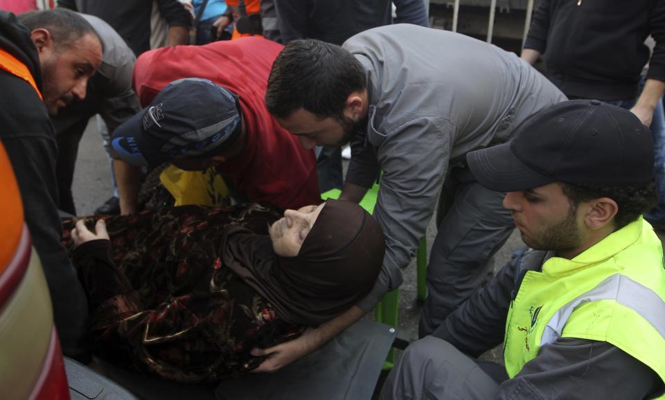 Civil Defense personnel help a woman at the scene of a bomb blast in the Haret Hreik area, in the southern suburbs of the Lebanese capital Beirut