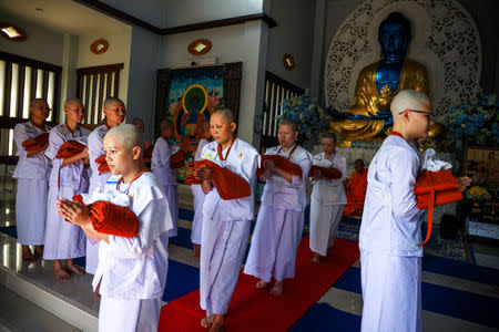 Thai women devotees carry their saffron robes during a mass female Buddhist novice monk ordination ceremony at the Songdhammakalyani monastery, Nakhon Pathom province, Thailand, December 5, 2018. REUTERS/Athit Perawongmetha