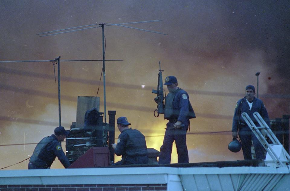 Philadelphia police officers patrol a rooftop in west Philadelphia after a police helicopter dropped a bomb on a building occupied by members of the Black liberation group MOVE on May 13, 1985.