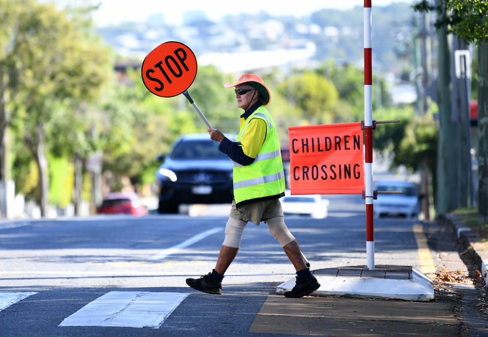 Pedestrian crossing attendant Peter performs his duty outside a primary school.