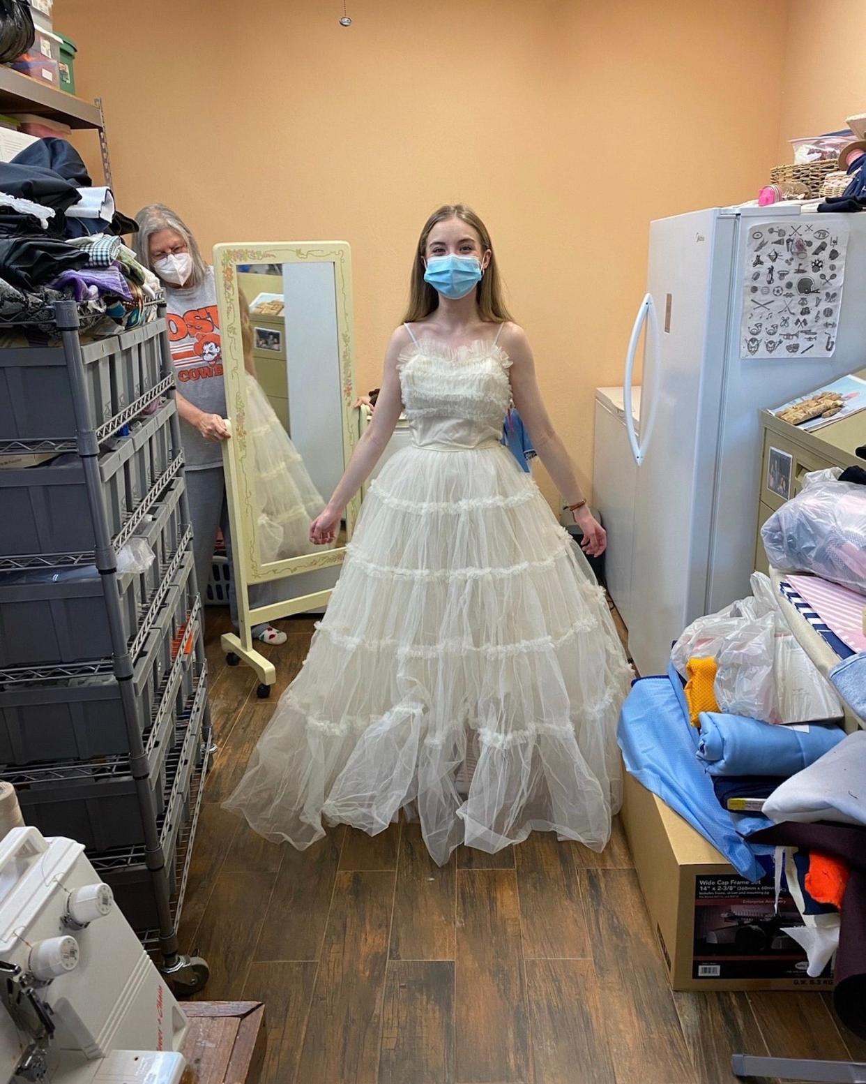 A bride stands in a seamstress store in a strapless wedding dress.