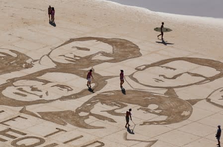 Local Basque sand artist Sam Dougados reproduces the faces of the G7 leaders in the sand on a beach in Biarritz on the eve of the Biarritz G7 summit