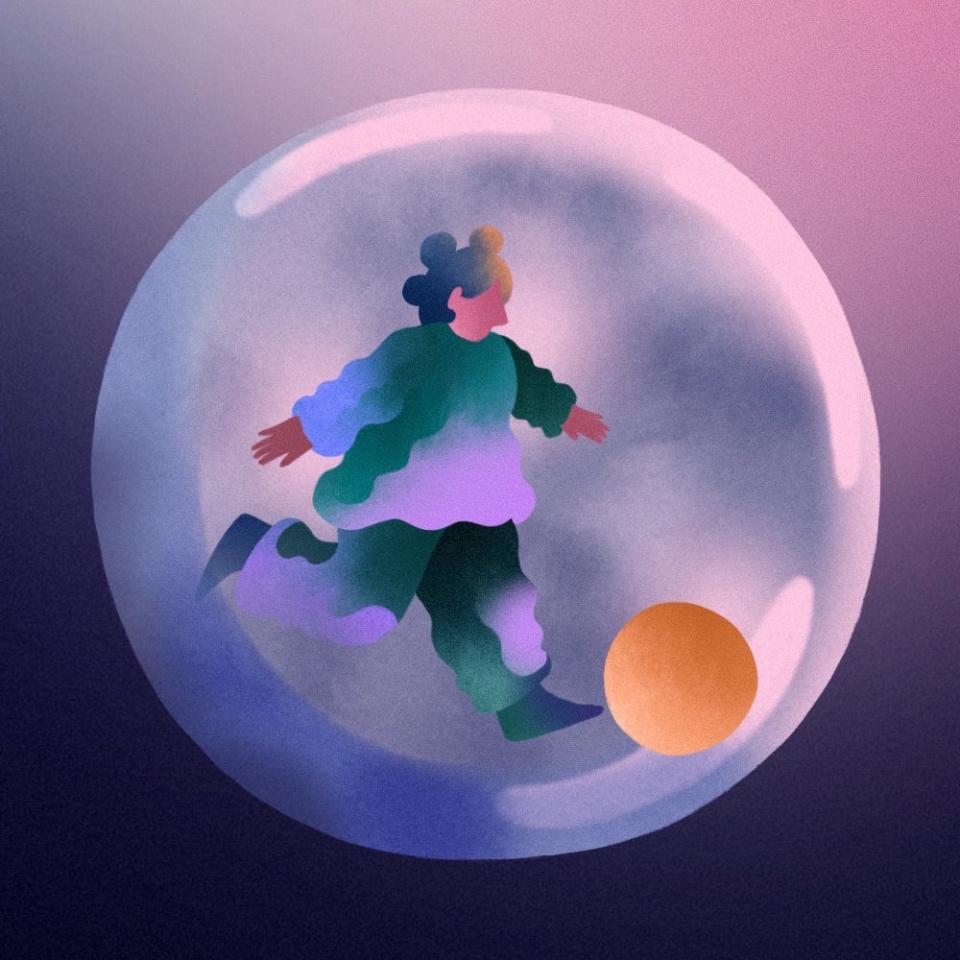 A young child kicks a ball while in encased in a transparent protective bubble.