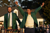 Hideki Matsuyama, of Japan, puts on the champion's green jacket after winning the Masters golf tournament as Dustin Johnson watches on Sunday, April 11, 2021, in Augusta, Ga. (AP Photo/David J. Phillip)