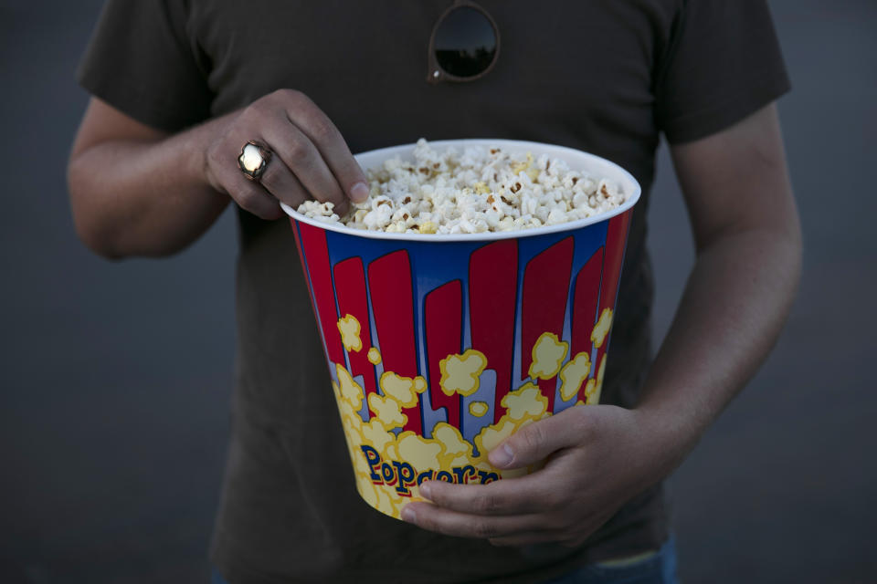 A moviegoer eats popcorn at Mission Tiki drive-in theater in Montclair, Calif., Thursday, May 28, 2020. California moved to further relax its coronavirus restrictions and help the battered economy. Flea markets, swap meets and drive-in movie theaters can resume operations. (AP Photo/Jae C. Hong)