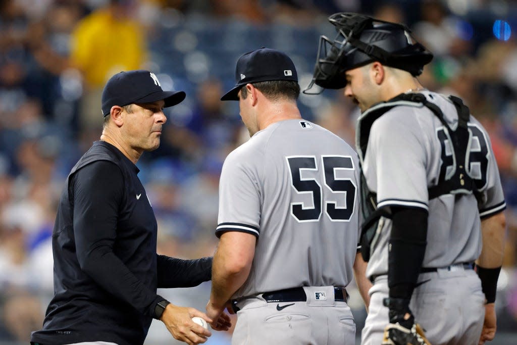 New York Yankees pitcher Carlos Rodon, center, is taken out by manager Aaron Boone, left, with catcher Austin Wells (88) on the mound during the first inning of a baseball game against the Kansas City Royals in Kansas City, Mo., Friday, Sept. 29, 2023. (AP Photo/Colin E. Braley)
