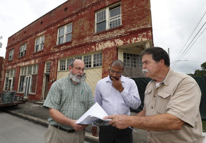 From left, Sidney Johnston, assistant director of grants, sponsored research and strategic initiatives at Stetson University; Mario Davis, executive director of the Greater Union Life Center nonprofit; and restoration expert Mark Shuttleworth look over plans for the J. W. Building in DeLand.