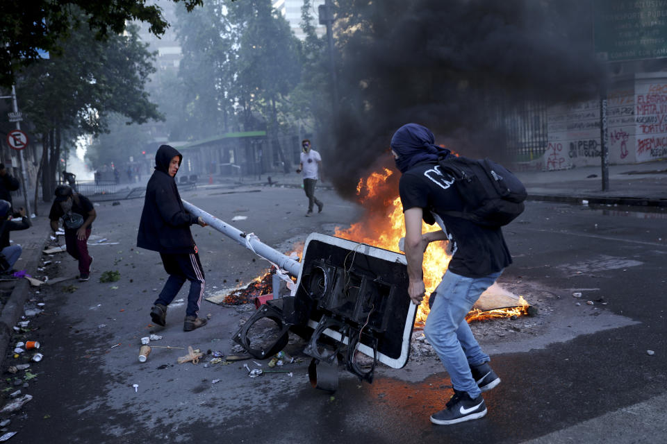 Anti-government protesters set up a barricade in Santiago, Chile, Tuesday, Oct. 29, 2019. Chileans gathered Tuesday for a 12th day of demonstrations that began with youth protests over a subway fare hike and have become a national movement demanding greater socio-economic equality and better public services in a country long seen as an economic success story. (AP Photo/Rodrigo Abd)