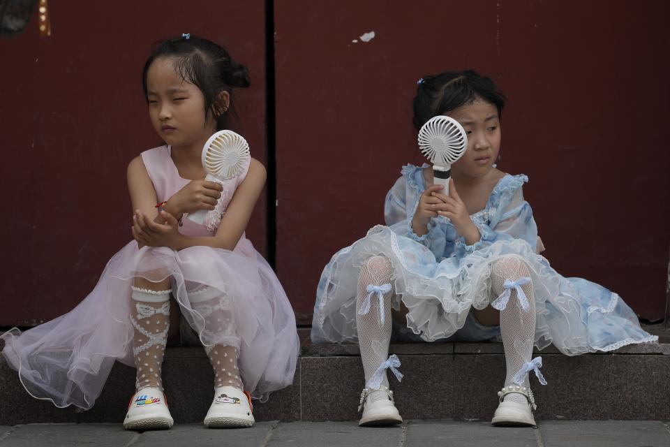 FILE - Children cool themselves with electric fans as they take a rest near the Forbidden City on a hot day in Beijing, June 25, 2023. The National Oceanic and Atmospheric Administration said Thursday, July 13, an already warming Earth steamed to its hottest June on record. (AP Photo/Andy Wong, File)