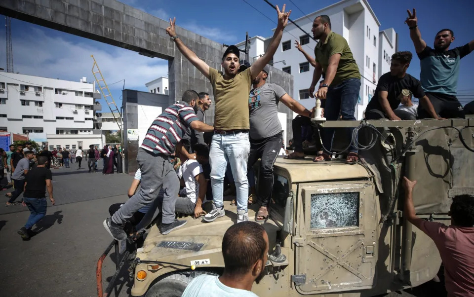 Palestinians ride an Israeli military jeep in the streets of Gaza during the storming of Israeli settlements by militants