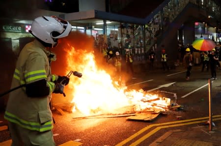 A firefighter extinguishes a fire set by anti-extradition bill protesters during a protest in Causeway Bay, Hong Kong