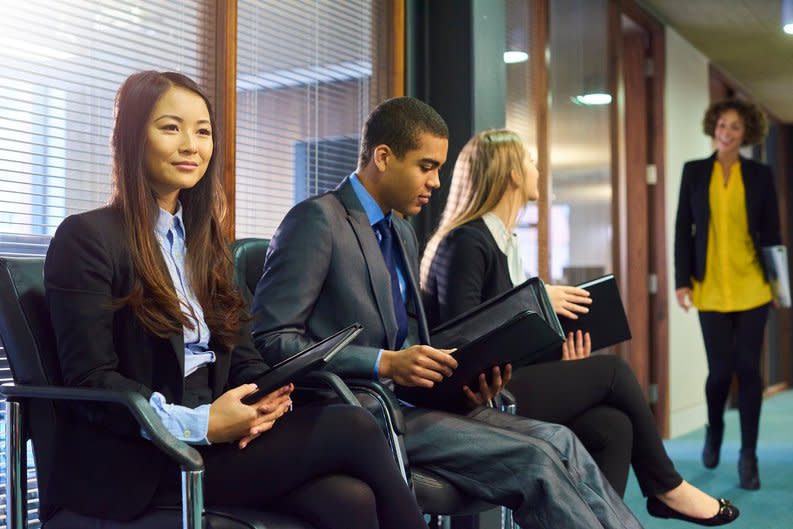 Three people are sitting in an office, waiting to be interviewed.