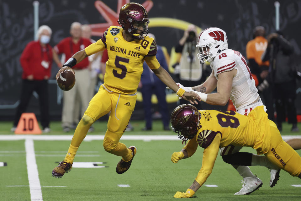 Arizona State quarterback Jayden Daniels (5) avoids a tackle by Wisconsin linebacker Nick Herbig (19) during the first half of the Las Vegas Bowl NCAA college football game Thursday, Dec. 30, 2021, in Las Vegas. (AP Photo/L.E. Baskow)