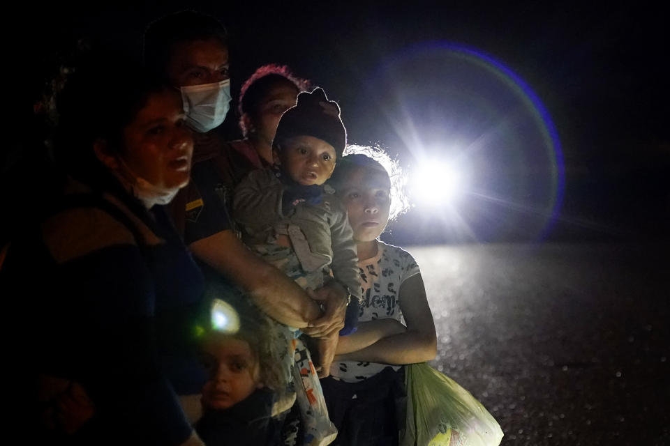 FILE - In this May 17, 2021 file photo, a group of migrants mainly from Honduras and Nicaragua wait along a road after turning themselves in upon crossing the U.S.-Mexico border, in La Joya, Texas. The U.S. Homeland Security Department says thousands of asylum-seekers whose claims were dismissed or denied under a Trump administration policy that forced them to wait in Mexico for their court hearings will be allowed to return for another chance at humanitarian protection. (AP Photo/Gregory Bull, File)