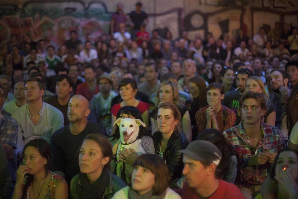 A dog sits between hundreds of German soccer fans a courtyard of a restaurant at Berlin's district Mitte during the screening of the Euro 2012 quarter final soccer match between Germany and Greece in Berlin, Friday, June 22, 2012. (AP Photo/Markus Schreiber)
