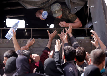 A Russian soldier distributes water to civilians who fled eastern Ghouta, at a shelter in Adra near Damascus, Syria, March 20, 2018. REUTERS/Omar Sanadiki