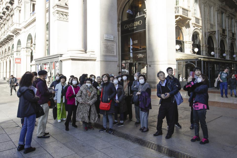 Tourists, some of them wearing sanitary masks, stand next to the Vittorio Emanuele Gallery in downtown Milan, Italy, Monday, Feb. 24, 2020. Italy has been scrambling to check the spread of Europe's first major outbreak of the new viral disease amid rapidly rising numbers of infections and a third death, calling off the popular Venice Carnival, scrapping major league soccer matches in the stricken area and shuttering theaters, including Milan's legendary La Scala. (AP Photo/Luca Bruno)