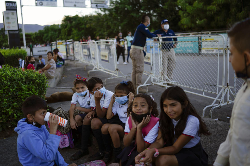 FILE - Venezuelan students wait for their school bus in Cucuta, Colombia, at sunrise Monday, Aug. 8, 2022, after crossing the border which Venezuela partially closed in 2015. A few days into their long break, teachers have been marching by the thousands around the country, threatening to strike when school resumes or possibly even to abandon their profession after the government paid them only a tiny fraction of their annual vacation bonus. (AP Photo/Matias Delacroix, File)