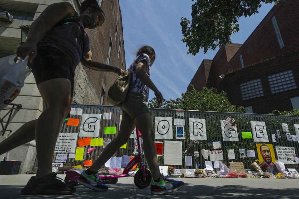 People observe the Harlem George Floyd Tribute Wall outside the Schomburg Center for Research in Black Culture Wednesday, June 10, 2020, in the Harlem neighborhood of New York. (AP Photo/Frank Franklin II)
