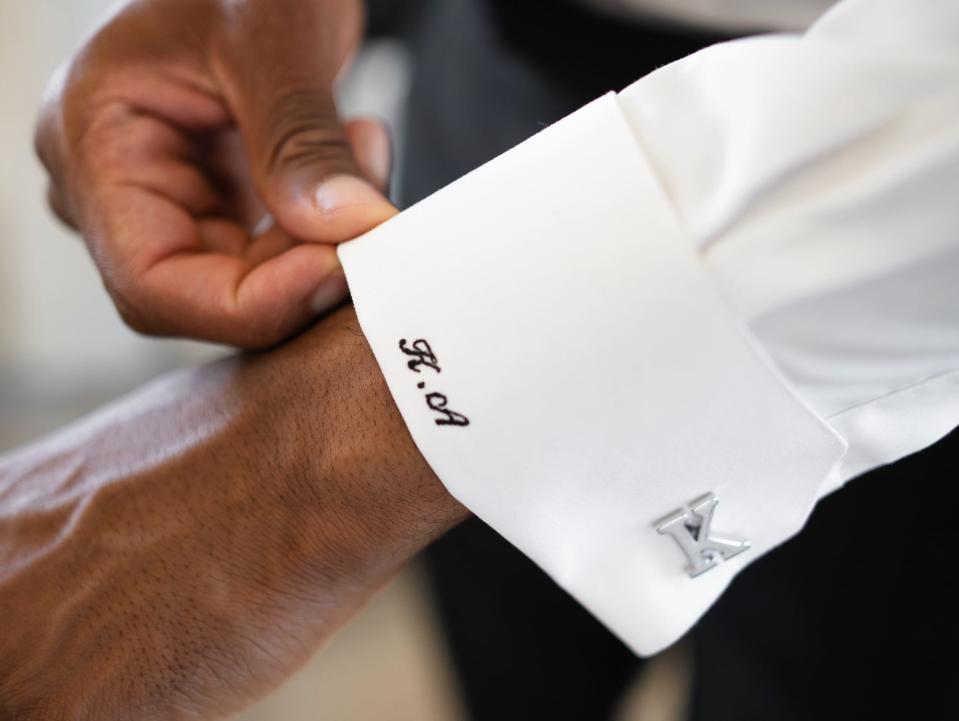 A man fixes his embroidered cuff sleeve.