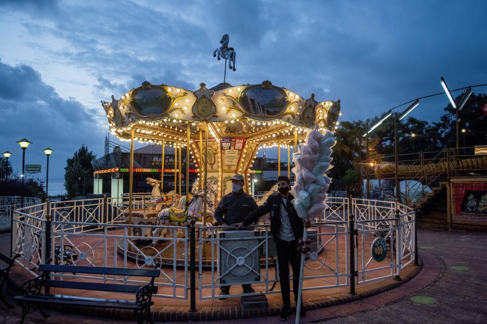 A cotton candy vendor waits for customers at an amusement park during the COVID-19 pandemic in Montevideo, Uruguay, Sunday, Jan. 31, 2021. (AP Photo/Matilde Campodonico)