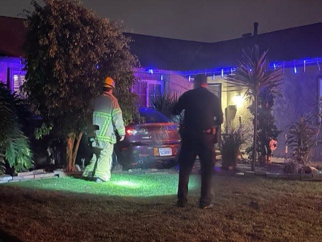 Ventura police and fire personnel investigate a car that crashed into a house on Jamestown Street early Saturday. No one in the house was injured.