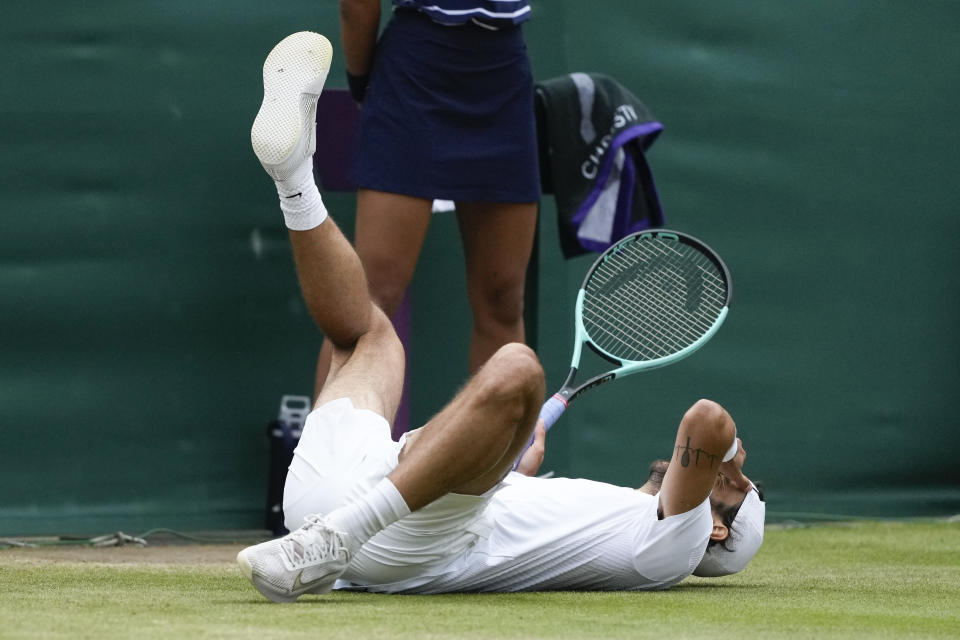 Lorenzo Musetti of Italy falls to the ground as he celebrates after defeating Giovanni Mpetshi Perricard of France in their fourth round match at the Wimbledon tennis championships in London, Monday, July 8, 2024. (AP Photo/Mosa'ab Elshamy)
