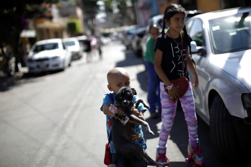 Hermes Soto carries Wicha the dog as he walks along a street in Mexico City