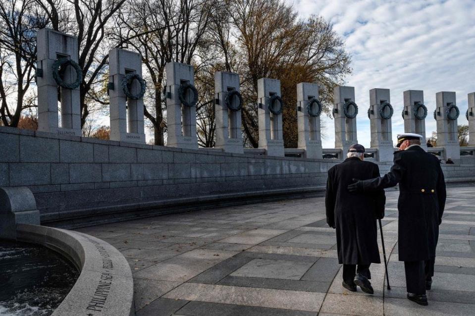 A WWII veteran is escorted to the National World War II Memorial's Freedom Wall during a 2021 event commemorating the 80th anniversary of the attack on Pearl Harbor.