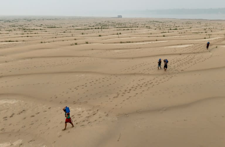 People carry drinking water along a sandbank of Madeira River in Paraizinho Community, in Humaita, Amazonas state, northern Brazil, on September 7, 2024 (MICHAEL DANTAS)