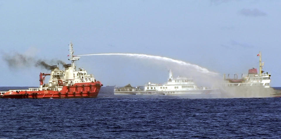 In this photo released by Vietnam Coast Guard, a Chinese ship, left, shoots water cannon at a Vietnamese vessel, right, while a Chinese Coast Guard ship, center, sails alongside in the South China Sea, off Vietnam's coast, Wednesday, May 7, 2014. Chinese ships are ramming and spraying water cannons at Vietnamese vessels trying to stop Beijing from setting up an oil rig in the South China Sea, according to Vietnamese officials and video evidence Wednesday, a dangerous escalation of tensions in disputed waters considered a global flashpoint. (AP Photo/Vietnam Coast Guard)