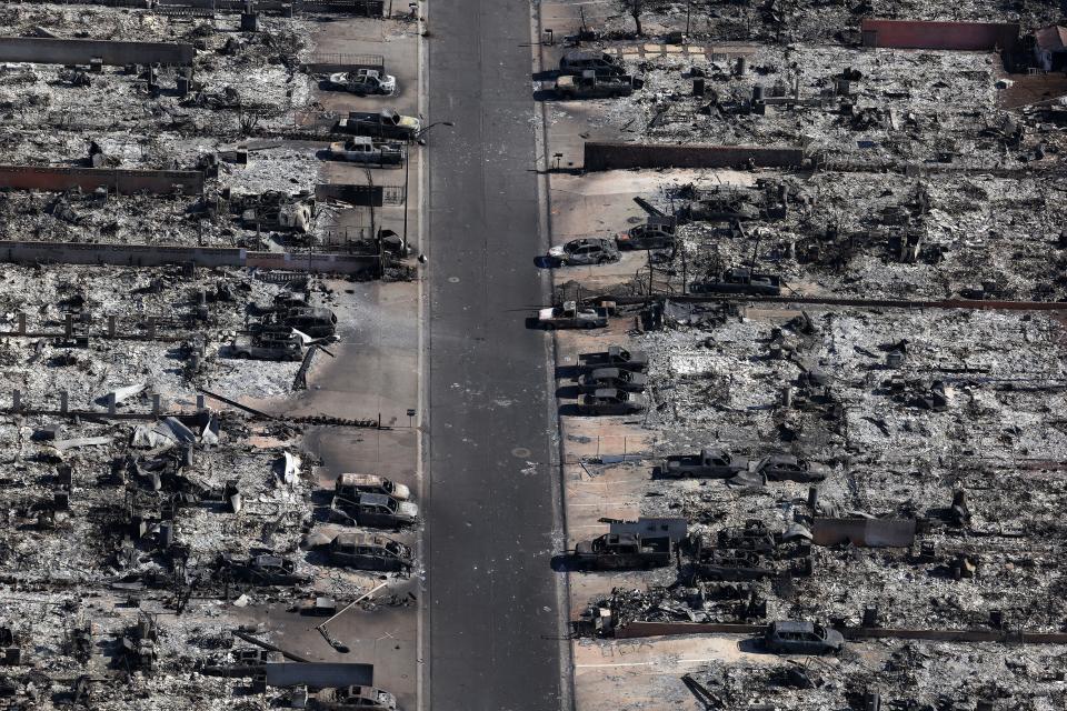 In an aerial view, burned cars sit in front of homes destroyed by a wildfire on Aug. 11 in Lahaina, Hawaii. Dozens of people were killed and thousands were displaced after a wind-driven wildfire devastated the town of Lahaina on Tuesday. Crews are continuing to search for missing people.