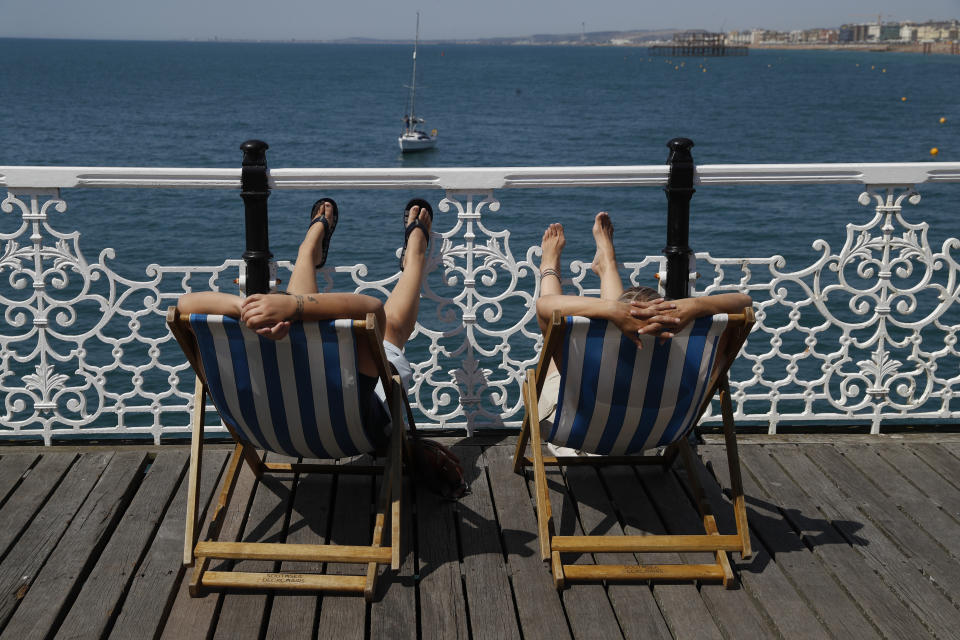 Two people relax in deck chairs as beachgoers enjoy the sunshine and sea on what is now Britain's hottest day of the year so far, in Brighton, England, Friday, July 31, 2020. Temperatures have reached 35C (95F) at London's Heathrow Airport. (AP Photo/Alastair Grant)