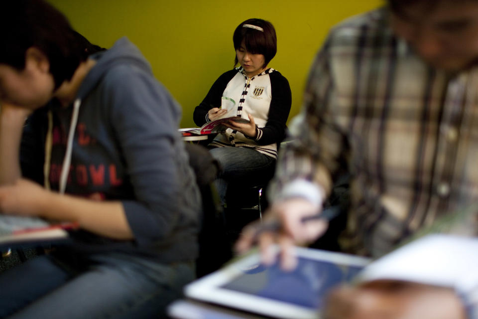 In this Sunday, Feb. 26, 2012 photo, Yin Shanshan, center, who plans to study for a Master's degree in Canada, checks her textbook during a French course of Alliance Francaise, an organization that promotes French language and culture, in Tianjin, China. Thousands of people in China are trying to write their own ticket out of the country - in French. Chinese desperate to emigrate have discovered a backdoor into Canada that involves applying for entry into the country's francophone province of Quebec - as long as you have a good working knowledge of the local lingo. (AP Photo/Alexander F. Yuan)