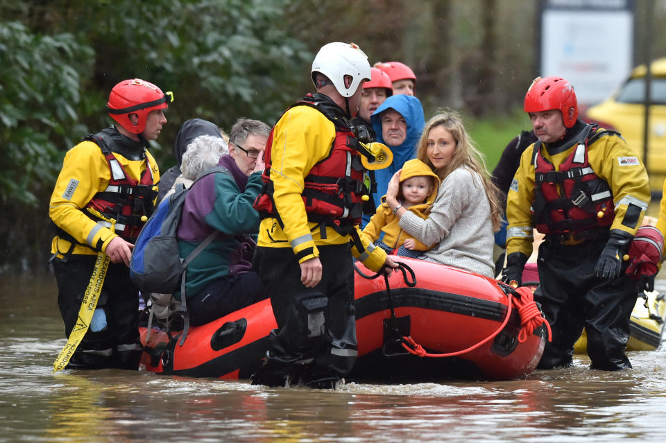 A family and other residents are dragged to safety in a dinghy. (PA)