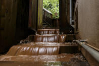 Water rushes down the stairs of a house near a mudslide that destroyed three homes on a hillside in Sausalito, Calif., Thursday, Feb. 14, 2019. Waves of heavy rain pounded California on Thursday, filling normally dry creeks and rivers with muddy torrents, flooding roadways and forcing residents to flee their homes in communities scorched by wildfires. (AP Photo/Michael Short)