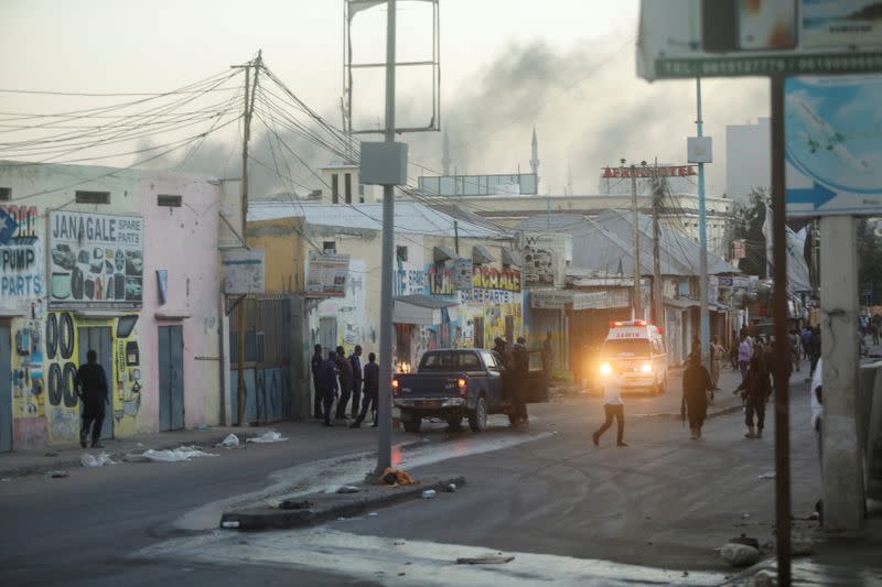 Somali security officers secure the scene of a car bomb explosion as paramedics await to rescue the injured in the Kilometre 4 area of Mogadishu