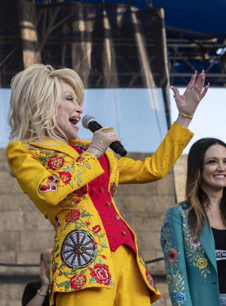 Dolly Parton performs during a headliner set curated by Brandi Carlile(at right)during the 60th anniversary of the Newport Folk Festival Saturday at Fort Adams State Park