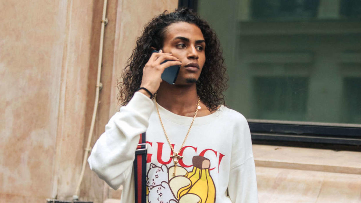 PARIS, FRANCE - OCTOBER 03: Model and Musician Luv Resval talks on the phone and wears a white Gucci banana sweatshirt, blue Gucci cross-body bag after the Lanvin show on October 03, 2021 in Paris, France. (Photo by Melodie Jeng/Getty Images)