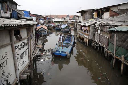 A boat passes through a canal along houses built over the seawall protecting Luar Batang, one of the oldest kampongs in Jakarta, dating back to the16th century, in north Jakarta October 7, 2014. REUTERS/Darren Whiteside